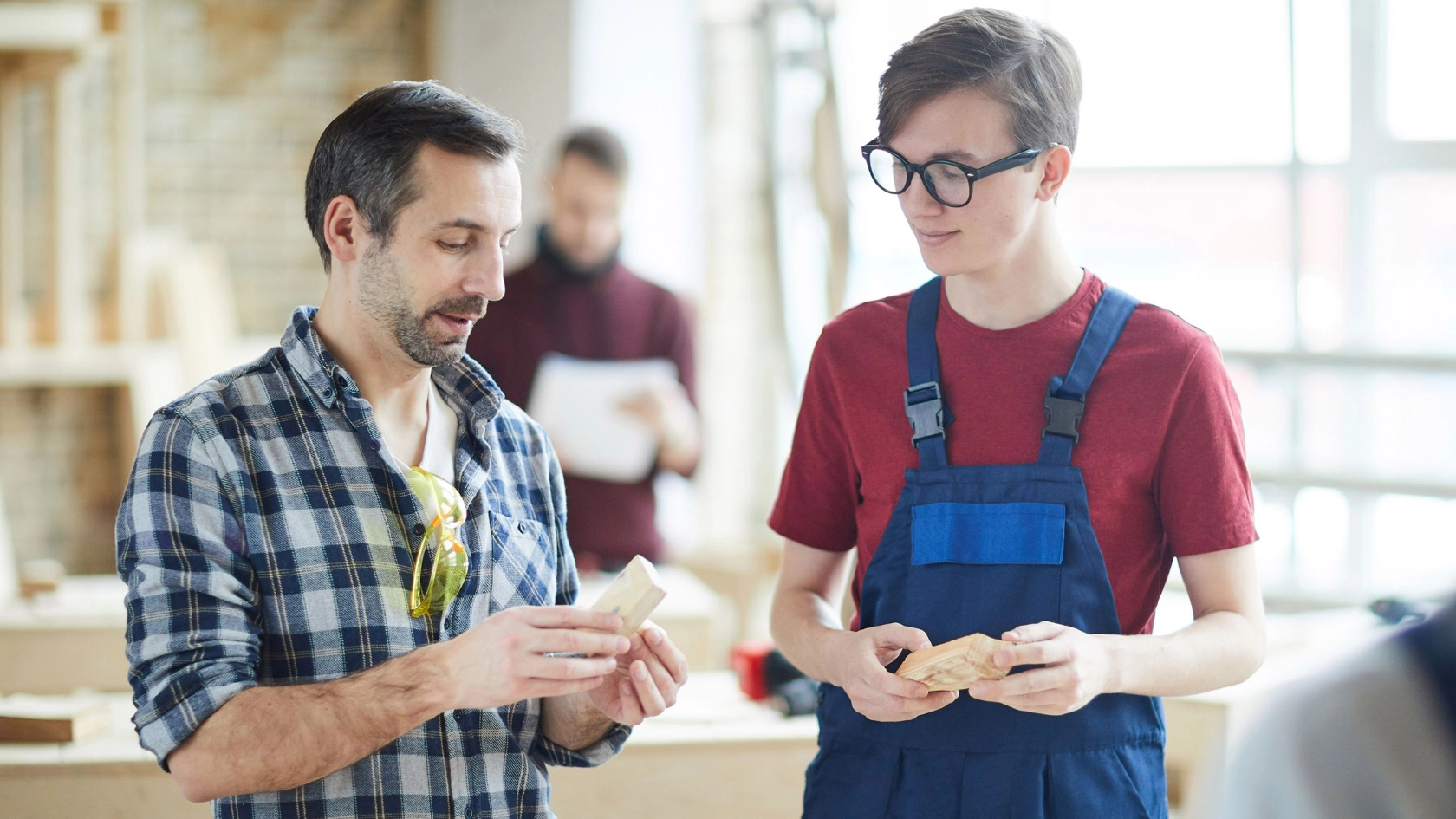 Auszubildender und Meister im Gespräch in einer Schreinerwerkstatt