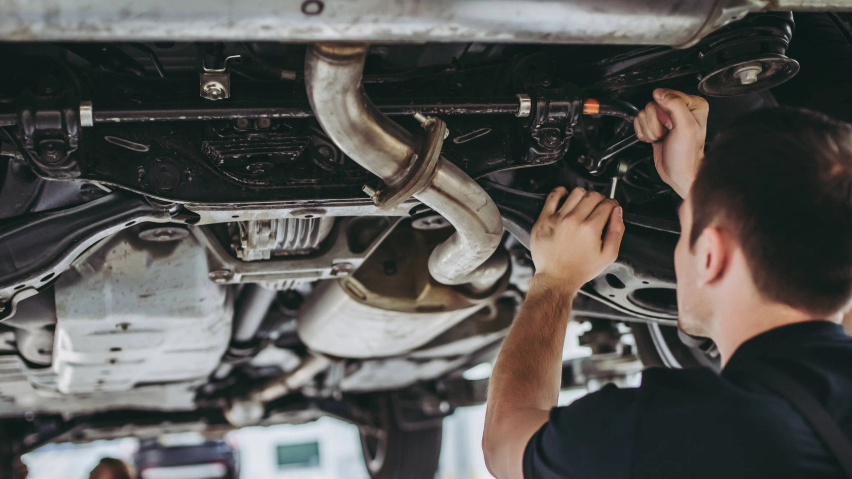 Zwei Männer stehen unter einer Hebebühne und arbeiten an einem Auto.