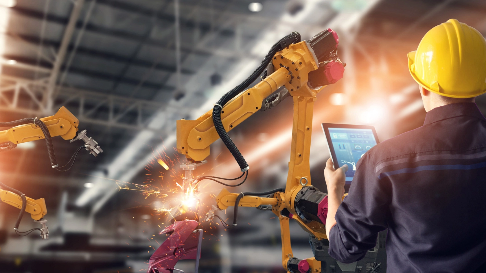 Ingenieur steuert mit Tablet einen Schweißroboter