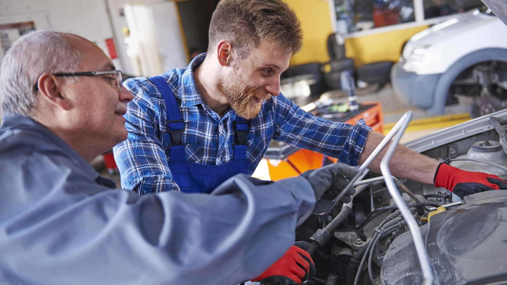 Zwei Kfz-Mechatroniker inspizieren den Motor eines Autos