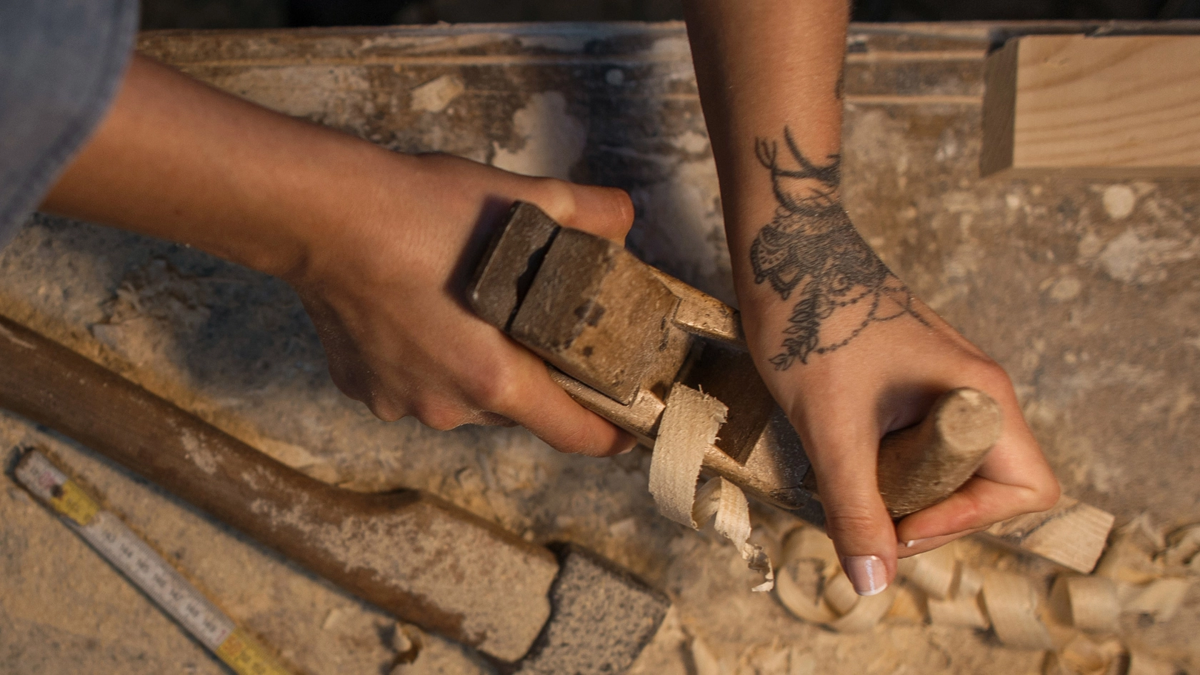 Weibliche Hände mit einer Tätowierung bei der Holzbearbeitung