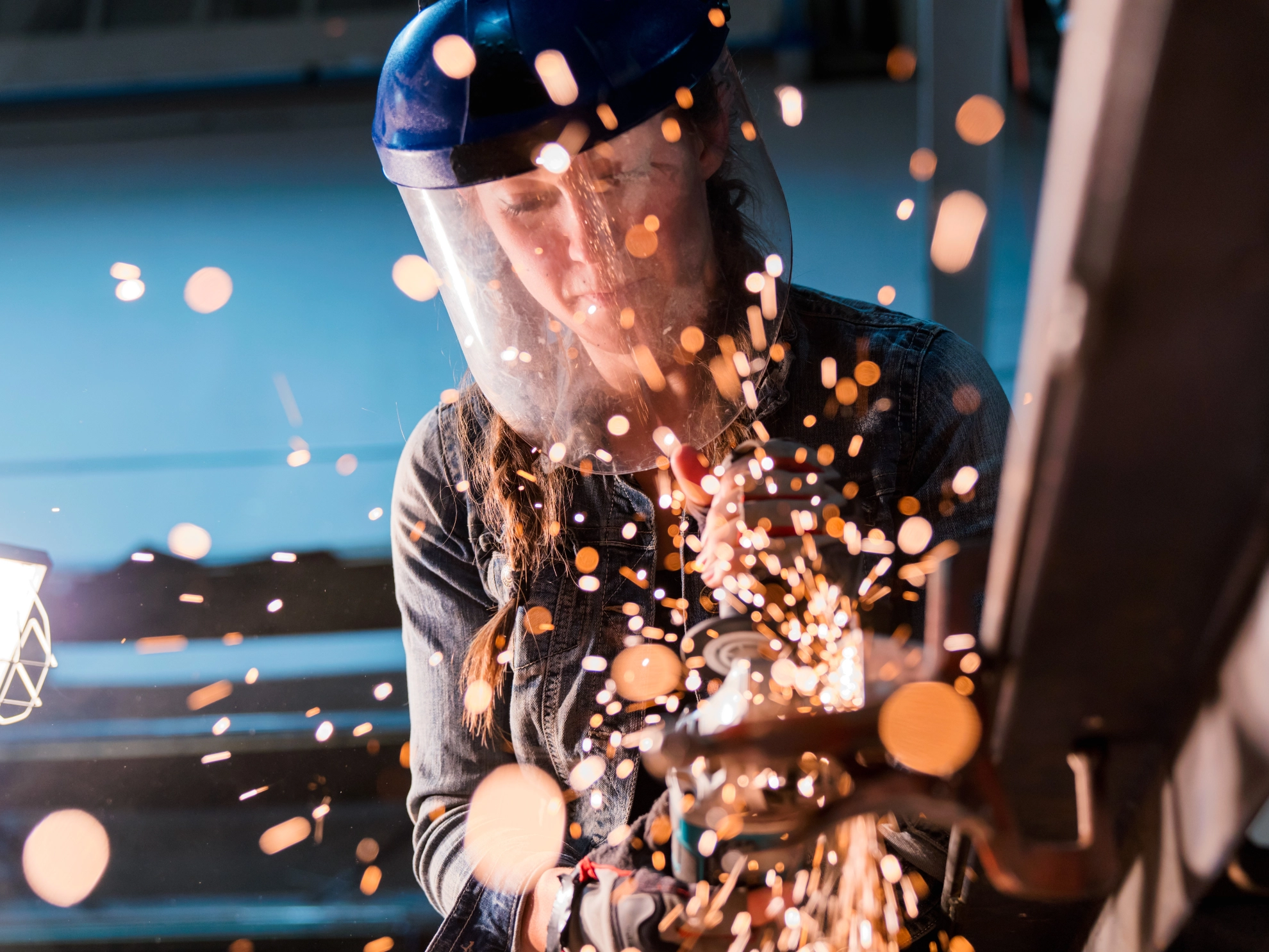 Eine Handwerkerin arbeitet mit einem Winkelschleifer in einer Werkstatt