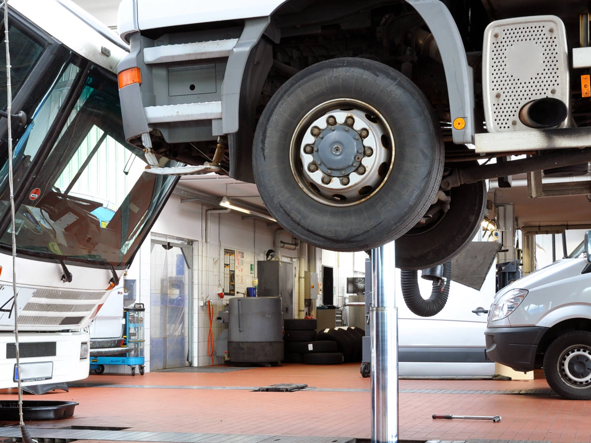 Ein Lkw auf einer Hebebühne. Ein Lieferwagen im Hintergrund.