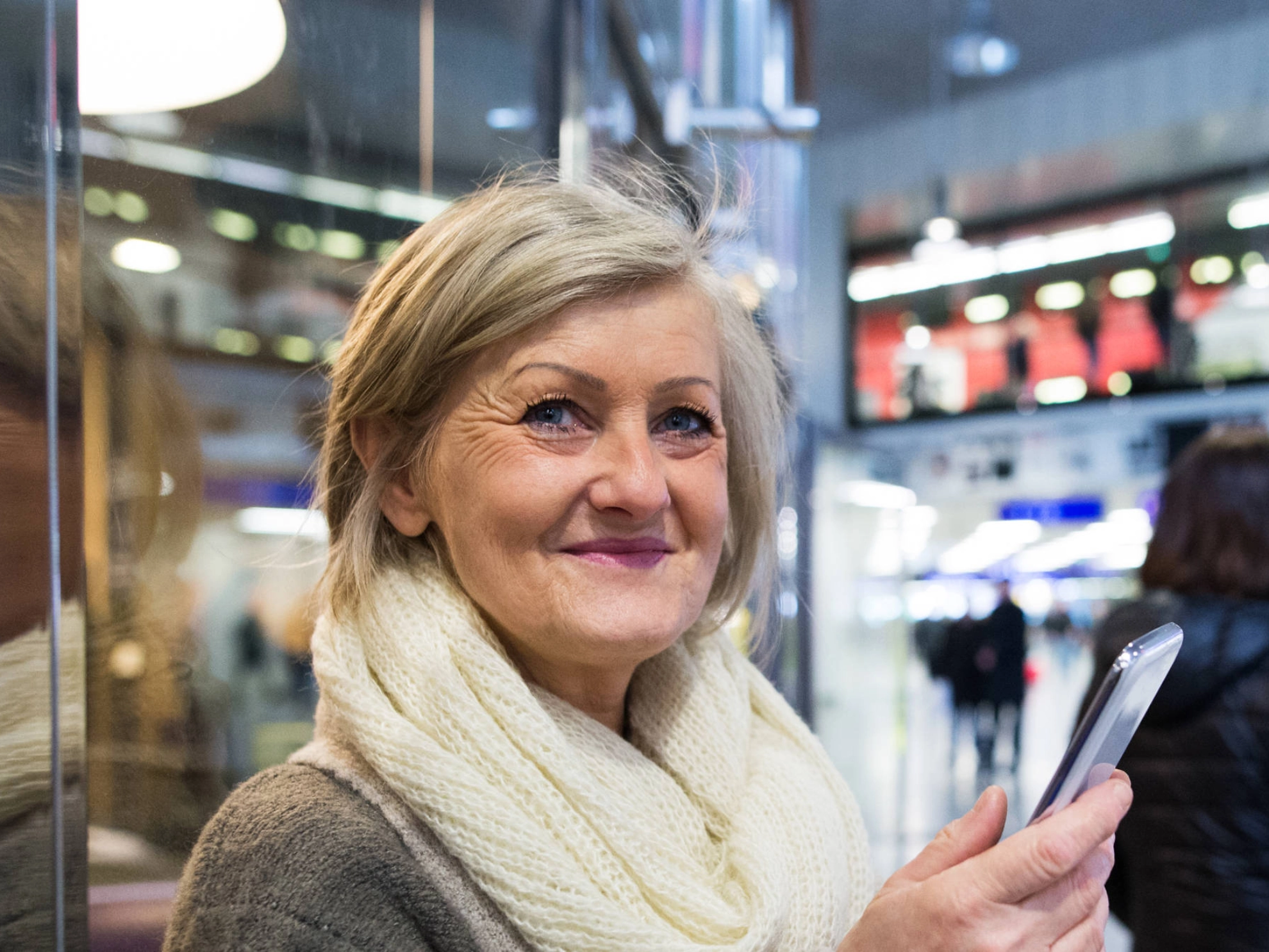Eine ältere Frau mit einem Smartphone in der Hand.