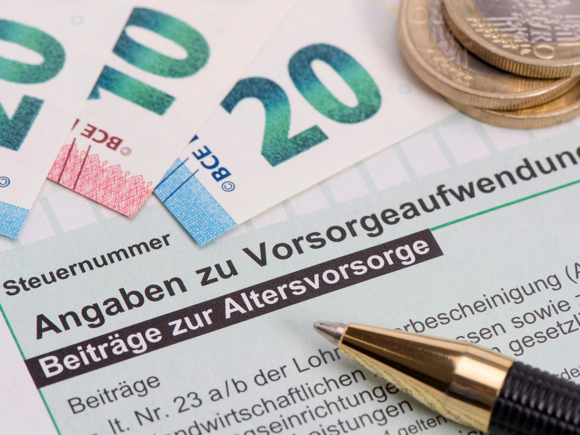 Geldscheine und Münzen liegen auf einem Formular zur Altervorsorge